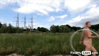 Exhibitionist girl spins hoop in Russian field