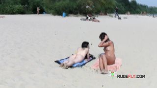 Nude beach girl sunbathes next to her man outdoors