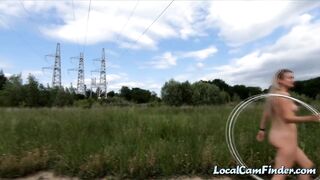 Exhibitionist girl spins hoop in Russian field